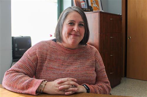  Jody posing while sitting at a table by a window 